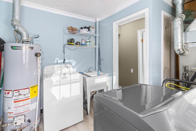 washroom with washing machine and clothes dryer, laundry area, gas water heater, and light wood-type flooring