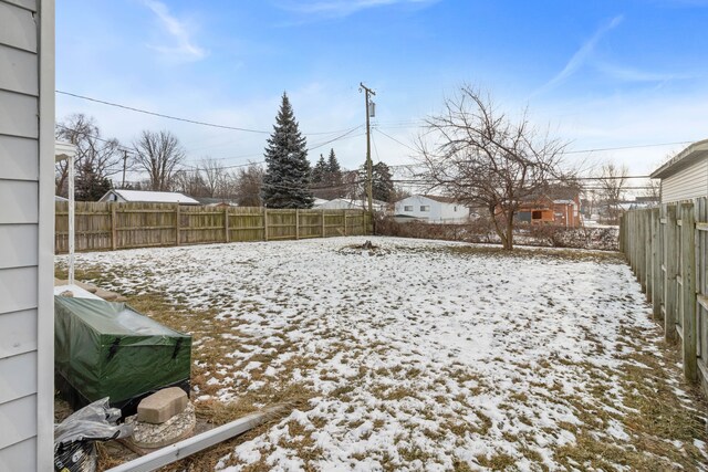 yard layered in snow with a fenced backyard