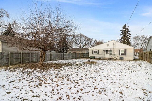 snow covered back of property featuring central air condition unit and a fenced backyard