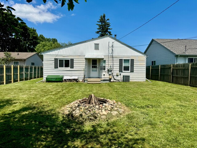 back of property featuring an outdoor fire pit, fence private yard, central AC, and a yard