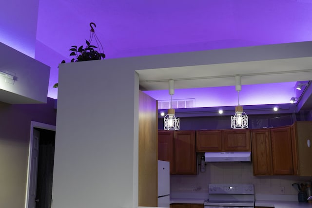 kitchen with brown cabinets, range with electric cooktop, under cabinet range hood, freestanding refrigerator, and decorative backsplash