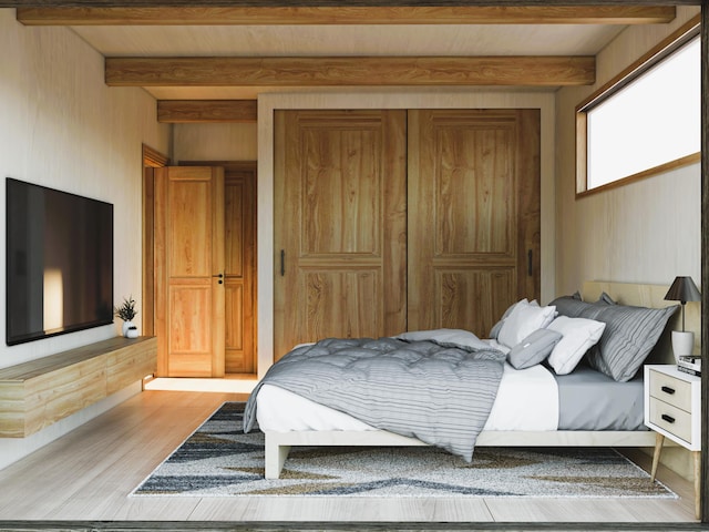 bedroom featuring a closet, beam ceiling, and light wood finished floors