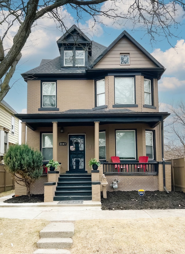 traditional style home featuring covered porch and brick siding