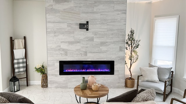 sitting room with marble finish floor, a fireplace, and baseboards