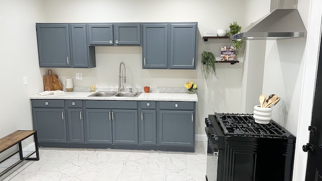 kitchen featuring a sink, marble finish floor, light countertops, black range with gas stovetop, and wall chimney exhaust hood