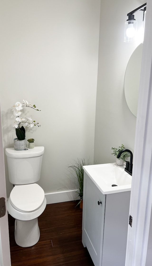 bathroom with baseboards, vanity, toilet, and wood finished floors