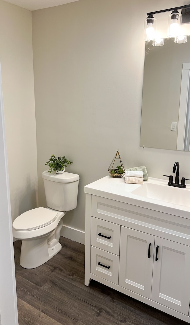 bathroom with toilet, baseboards, wood finished floors, and vanity