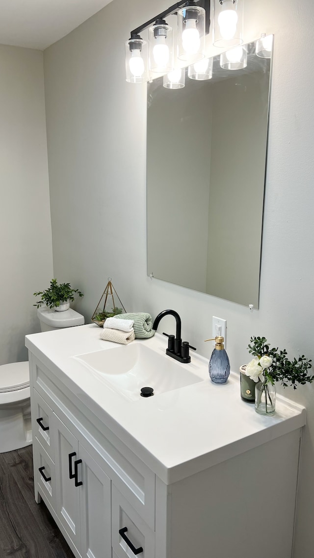 bathroom featuring toilet, wood finished floors, and vanity