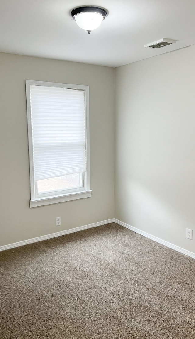 spare room featuring carpet floors, visible vents, and baseboards