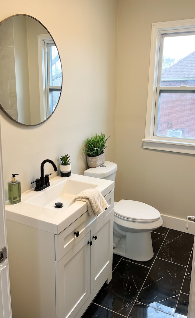 bathroom featuring marble finish floor, baseboards, vanity, and toilet