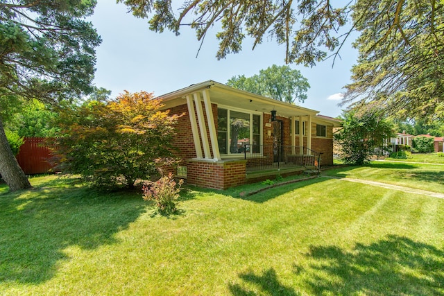 exterior space featuring a front yard, fence, and brick siding