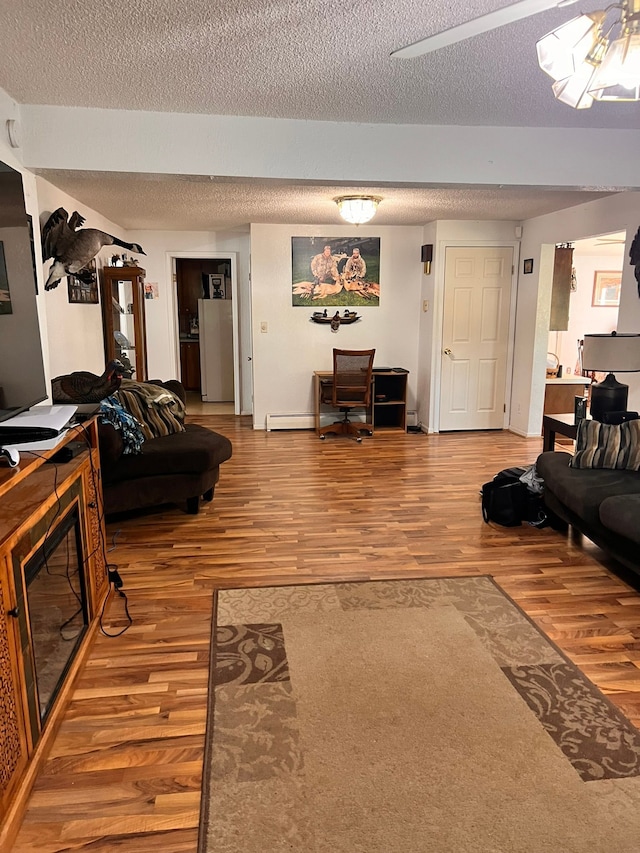 living area with a glass covered fireplace, a textured ceiling, and wood finished floors