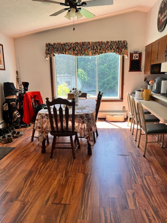 dining space featuring dark wood finished floors, ceiling fan, vaulted ceiling, a textured ceiling, and a baseboard heating unit