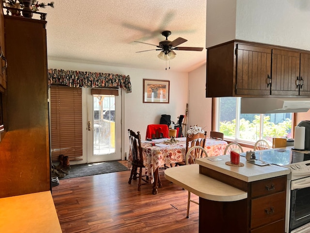 kitchen featuring white range with electric cooktop, light countertops, dark wood-type flooring, a textured ceiling, and plenty of natural light