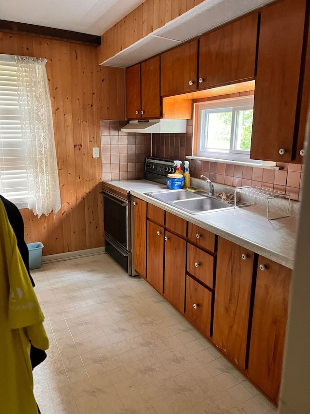 kitchen with electric stove, brown cabinets, light floors, light countertops, and wood walls