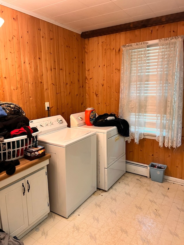 laundry room featuring a baseboard radiator, wood walls, cabinet space, light floors, and washer and clothes dryer