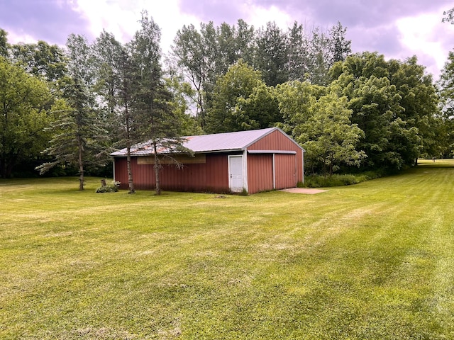 view of yard featuring a detached garage, an outdoor structure, and an outbuilding