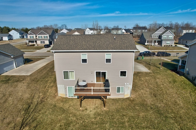 back of house with a residential view, a yard, and roof with shingles