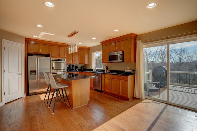 kitchen featuring stainless steel appliances, dark countertops, and light wood finished floors