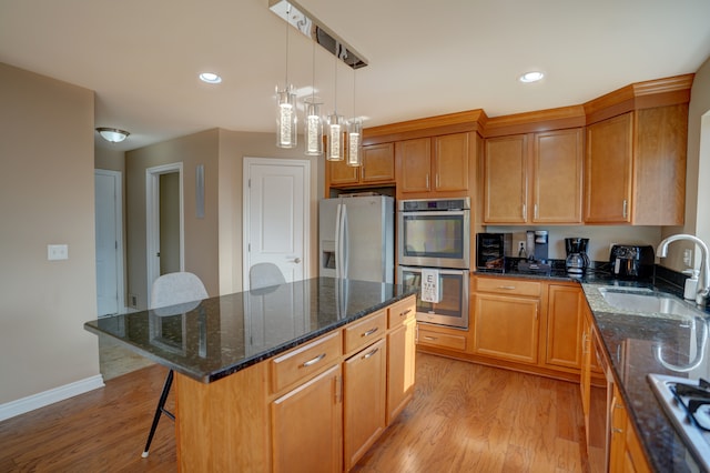 kitchen with a sink, a breakfast bar area, light wood-style floors, and stainless steel appliances