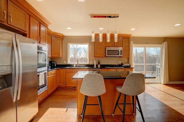 kitchen with a sink, stainless steel appliances, light wood-style floors, a kitchen breakfast bar, and a center island