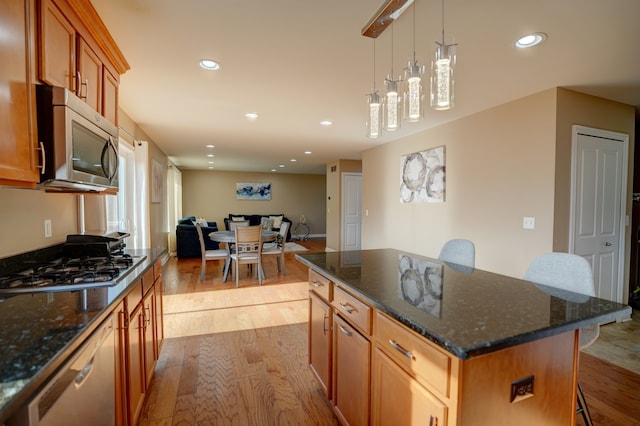 kitchen with brown cabinets, appliances with stainless steel finishes, wood finished floors, and a breakfast bar