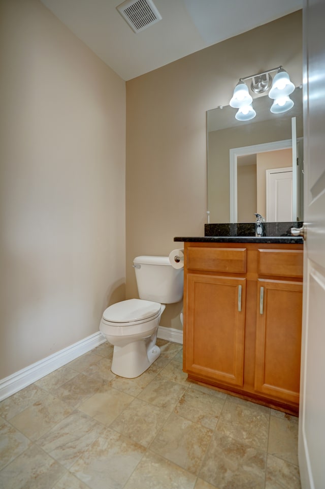 half bathroom featuring vanity, toilet, baseboards, and visible vents