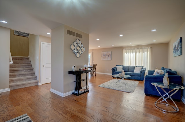 living area featuring wood finished floors, visible vents, baseboards, recessed lighting, and stairs