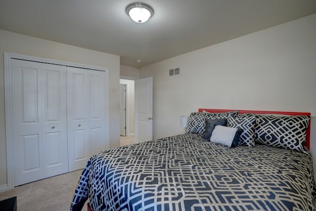 bedroom featuring light colored carpet, visible vents, and a closet