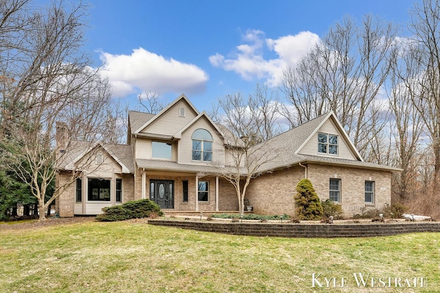 traditional-style home featuring a shingled roof, brick siding, and a front lawn