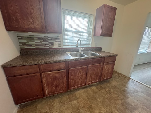 kitchen with tasteful backsplash, dark countertops, and a sink