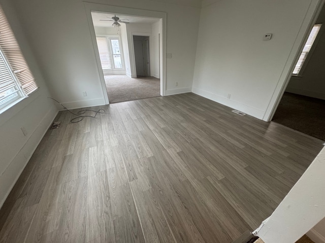 unfurnished living room with visible vents, baseboards, and wood finished floors