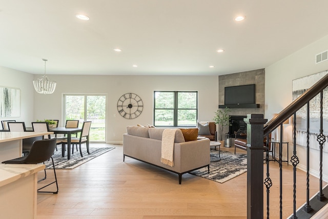 living area with light wood finished floors, a fireplace, visible vents, and a healthy amount of sunlight