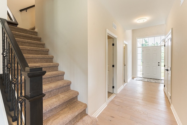 entrance foyer featuring light wood-type flooring, stairway, baseboards, and visible vents