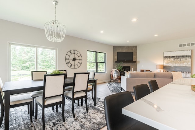 dining area with a notable chandelier, a fireplace, recessed lighting, visible vents, and wood finished floors