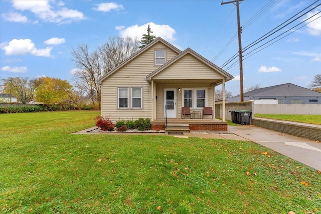 bungalow with covered porch, a front lawn, and fence