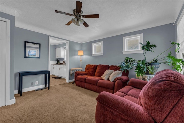 living area with light carpet, a textured ceiling, baseboards, and a ceiling fan