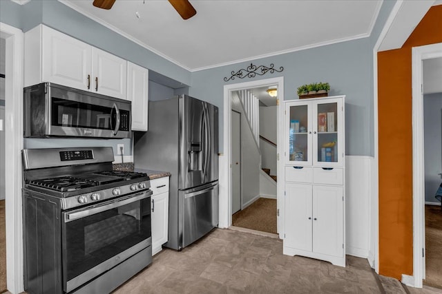 kitchen with stainless steel appliances, a ceiling fan, crown molding, and white cabinetry