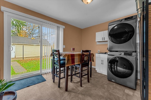 laundry area with cabinet space, baseboards, and stacked washer and dryer