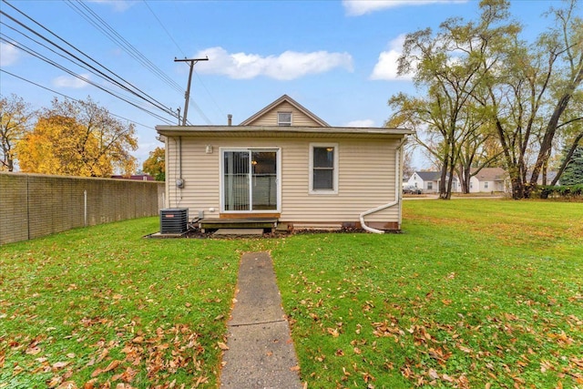 rear view of property featuring central air condition unit, fence, and a lawn