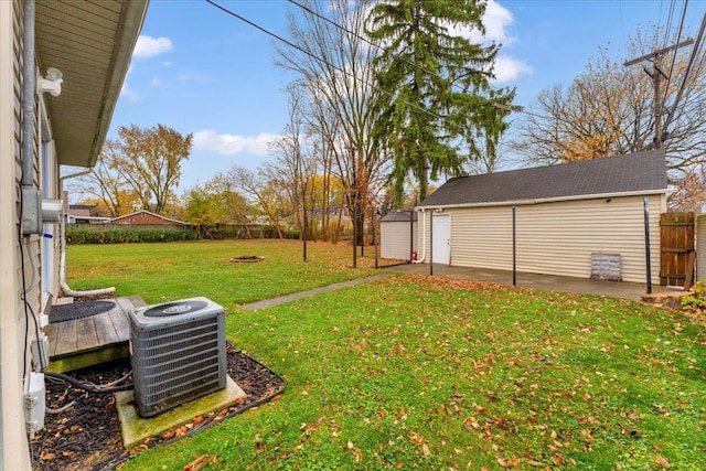 view of yard with an outbuilding, central AC, a fenced backyard, a fire pit, and a patio area