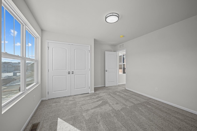 unfurnished bedroom with a closet, carpet, visible vents, and baseboards