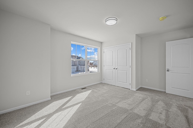 unfurnished bedroom with carpet floors, a closet, visible vents, and baseboards