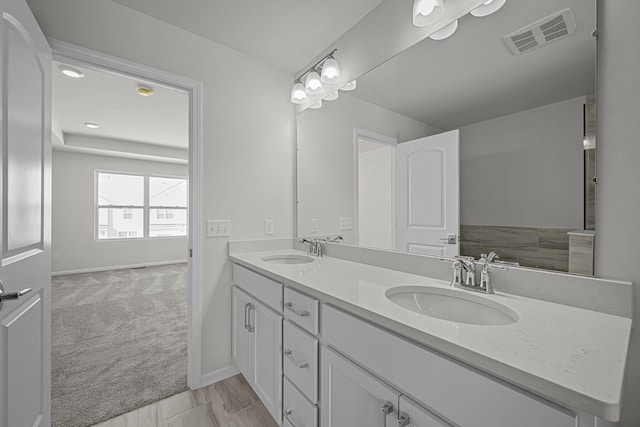 full bathroom with double vanity, baseboards, visible vents, and a sink