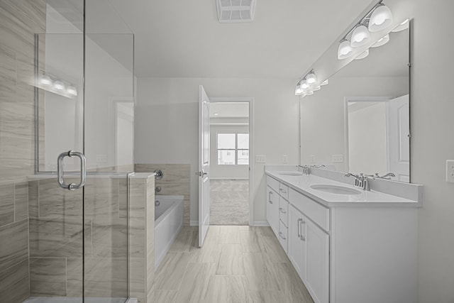 bathroom featuring a bath, double vanity, a sink, and visible vents