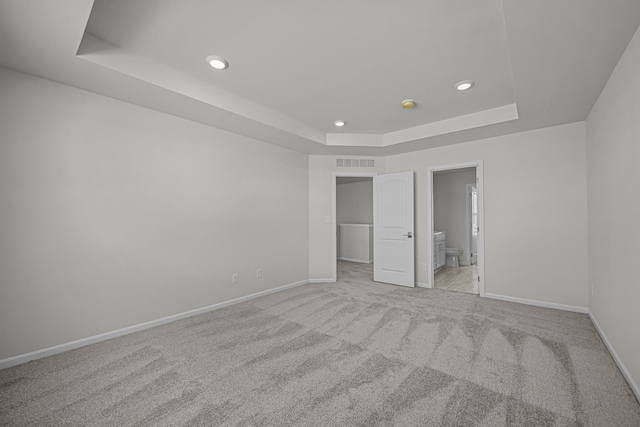 unfurnished bedroom featuring recessed lighting, visible vents, baseboards, a tray ceiling, and carpet