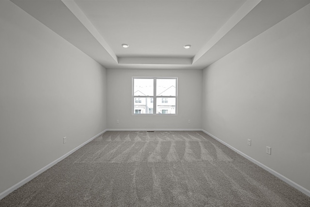 carpeted empty room featuring baseboards and a tray ceiling