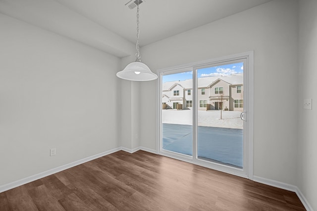 unfurnished dining area featuring dark wood-type flooring, visible vents, and baseboards