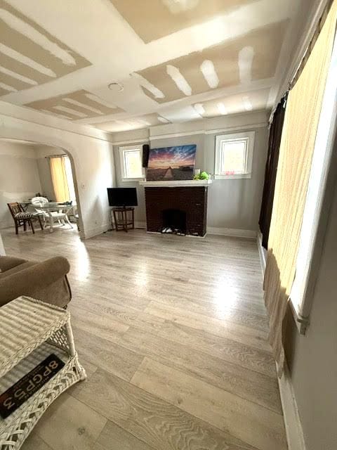 interior space with light wood-type flooring, plenty of natural light, a fireplace, and arched walkways