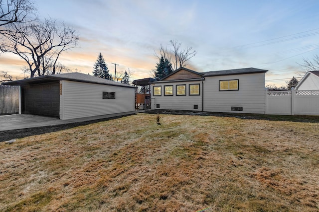 rear view of house featuring a yard, crawl space, an outdoor structure, and fence